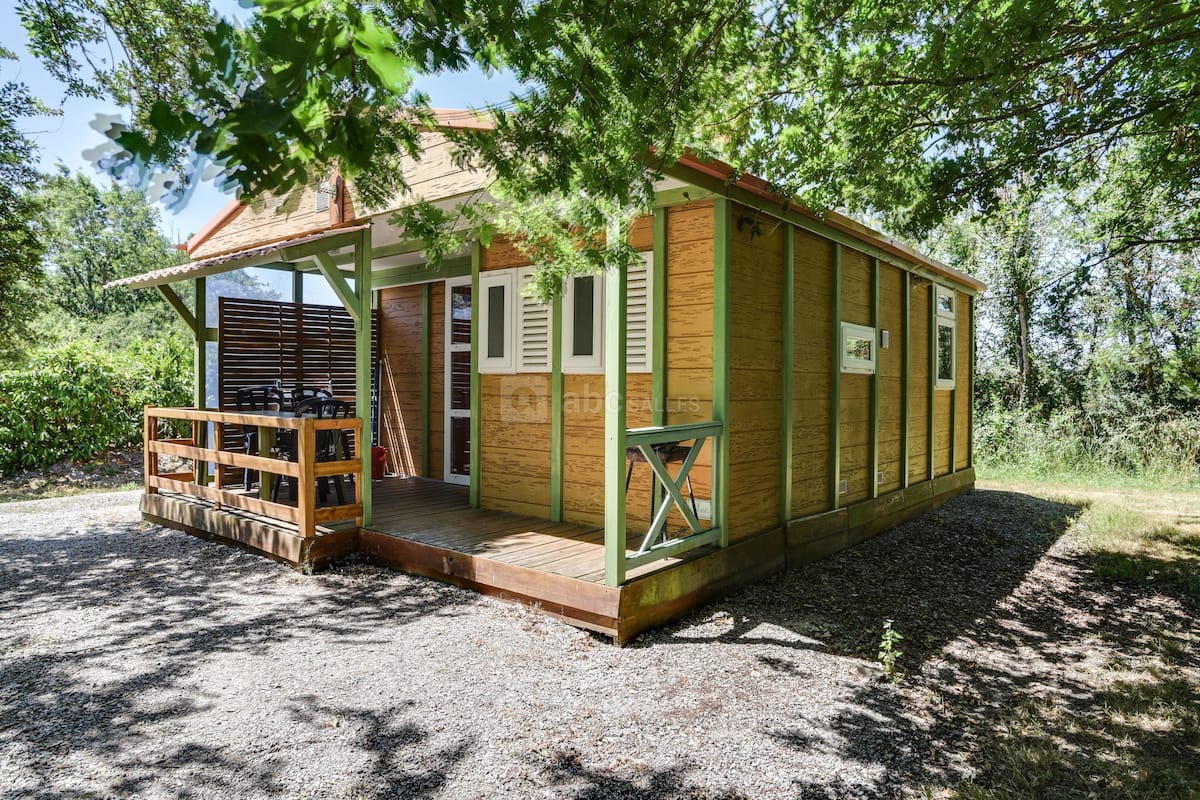Une petite cabane en bois dotée d’un porche, entourée d’arbres.