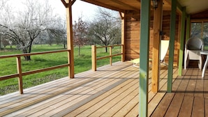 Eine Holzterrasse mit Geländer, einem grünen Stuhl und einem Tisch.