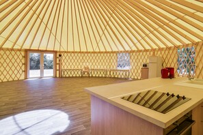 A spacious interior with a wooden floor, a central kitchen area with a sink and stove, and a large window providing natural light. - Le Domaine de La Barre (Gourgé)