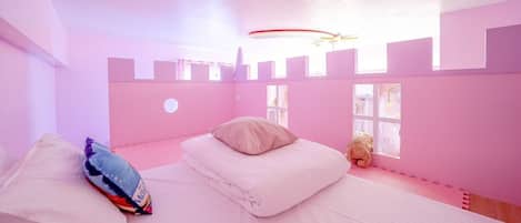 A pink-themed bedroom with a bed, pillows, and a teddy bear.