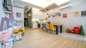 A modern kitchen with white cabinets, a dining area with a table and chairs, and a small Christmas tree. - Yilan 1955 Kids Friendly B&B (Wujie)