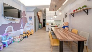 A modern kitchen with a wooden dining table, yellow chairs, and a teddy bear on the table. - Yilan 1955 Kids Friendly B&B (Wujie)