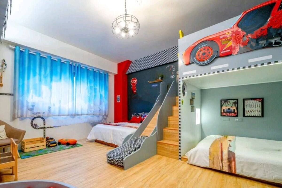 Une chambre adaptée aux enfants, avec des lits superposés, un espace de jeux et une fenêtre avec des rideaux.