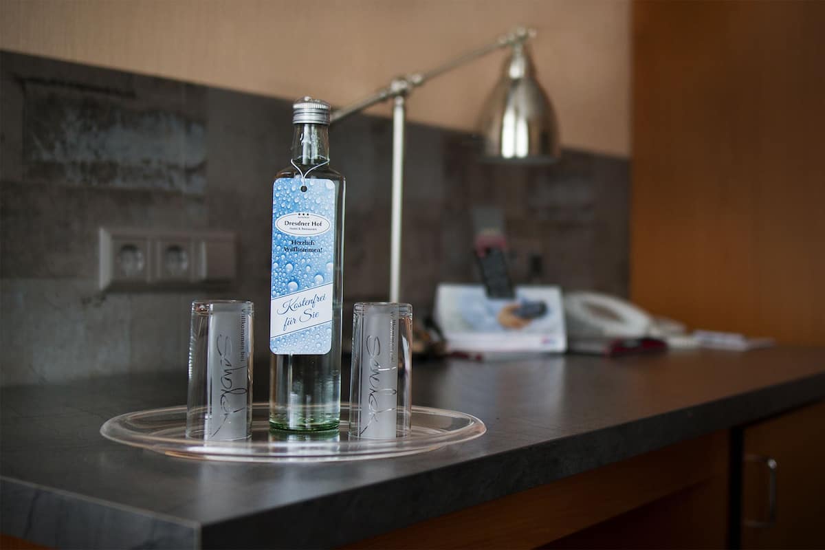 Une bouteille de Dreamer Hot water avec une étiquette, deux verres et une lampe sur un comptoir.
