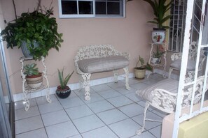 Eine Terrasse mit einer weißen Bank, Topfpflanzen und einem weißen Geländer.