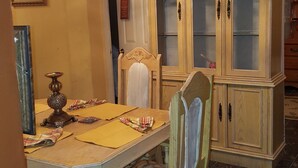 A dining area with a wooden table, chairs, a cabinet with glass doors, and a hanging light fixture. - Dream Vacation ST Catherine Jamaica - Guest Suites for Rent in Spanish Town (Spanish Town)