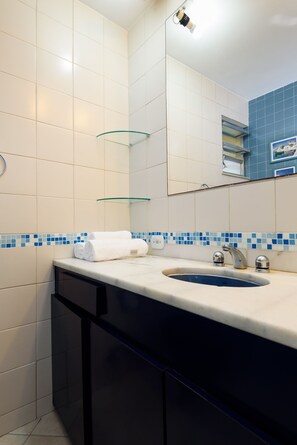 Un baño con lavamanos, espejo y salpicadero de azulejos azules.