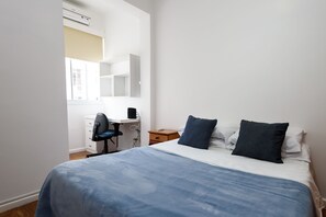 Un dormitorio con cama, escritorio y silla.