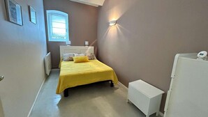 A small bedroom with a bed, bedside table, and a nightstand.