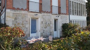 A building with two doors, a balcony, and a table set for dining.