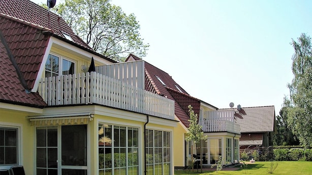Een woongebouw met een overdekte patio, een omheind balkon en een keurig onderhouden gazon.