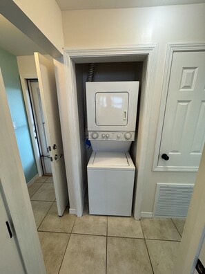 A laundry room with a washer and dryer, a door, and a vent.