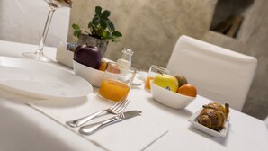Ein Frühstückstisch mit Orangensaft, Obstschale, Croissant und Glas Milch.
