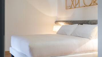 A modern bedroom with a wooden ceiling, a bed with white bedding, and a wall-mounted sign that reads "EXPLORER".