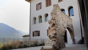 Ein Gebäude mit einer steinernen Fassade, Bogenfenstern und einer Holzterrasse.