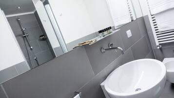 A modern bathroom with a large mirror, a white sink, and a shower area.