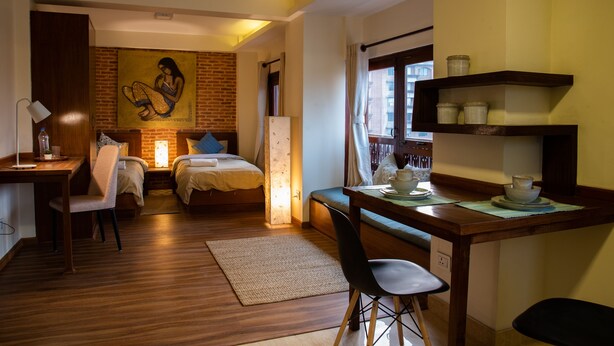 Ein kleines Hotelzimmer mit Bett, Schreibtisch, Stuhl und einem Bild an der Wand.