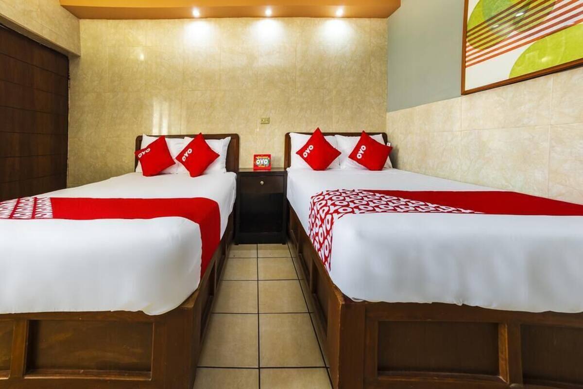 A hotel room with two beds, each with a red and white bedspread and matching pillows.