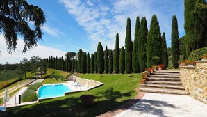 A landscaped garden with a swimming pool, stone steps, and tall trees. - Ginestra, house with outdoor patio and overlooking the common swimming pool (San Gimignano)