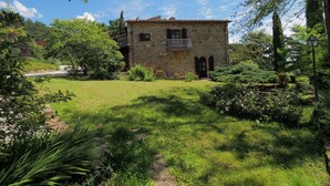 A stone building with a tiled roof, surrounded by lush greenery and a well-maintained lawn. - Ginestra, house with outdoor patio and overlooking the common swimming pool (San Gimignano)