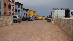 Un área de estacionamiento con varios coches y una furgoneta blanca.