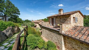 Un bâtiment en pierre avec un toit en tuiles, un balcon et un chemin en pierre.