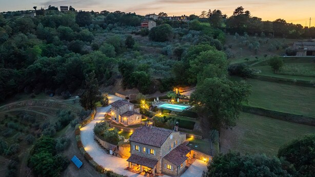 Une villa en pierre dotée d’une piscine, entourée d’une végétation luxuriante et bordée d’un sentier sinueux.
