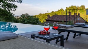 Une scène au bord de la piscine avec deux verres d’une boisson rouge, un bol de fraises et une petite table.