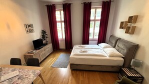 Una habitación con cama, escritorio, silla, televisión y planta.