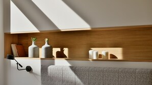Una habitación moderna con una estantería de madera que muestra libros, jarrones y velas.