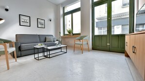 Una sala de estar moderna con un sofá gris, una mesita de centro y una puerta verde.