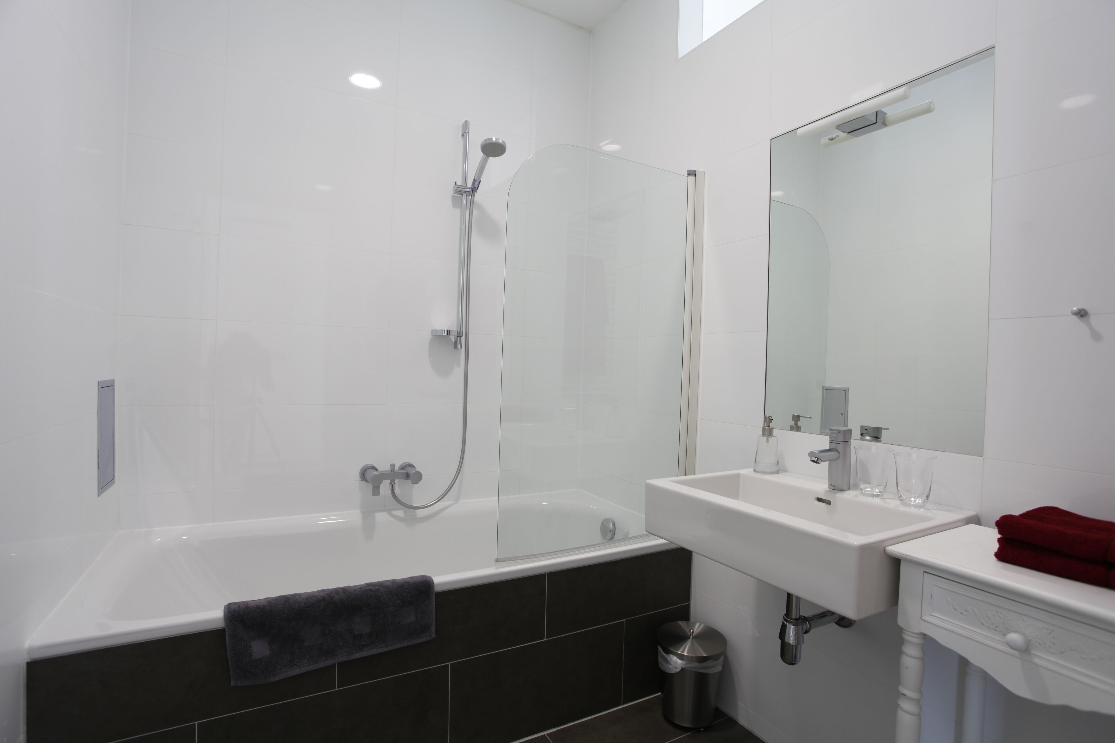 A modern bathroom with a glass-enclosed shower, a white sink, and a large mirror.