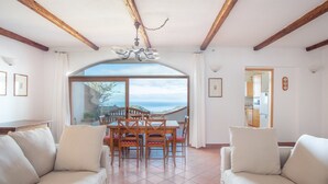 A living room with a dining area, large windows, and a view of the outdoors. - Our sea view house offers space on 400 square meters for 2-10 people (Magomadas (OR))