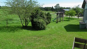 Un espacio al aire libre con césped, una estructura de juegos, un banco y un edificio al fondo.