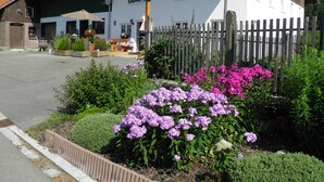 Un edificio de fachada blanca, valla de madera y jardín con flores moradas.