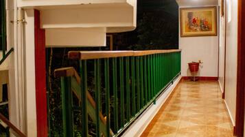 A staircase with a green railing, a tiled floor, and a painting on the wall.