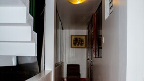 A hallway with a red patterned floor, white walls, and a staircase on the left. - Hotel Retama Machupicchu (Machu Picchu)