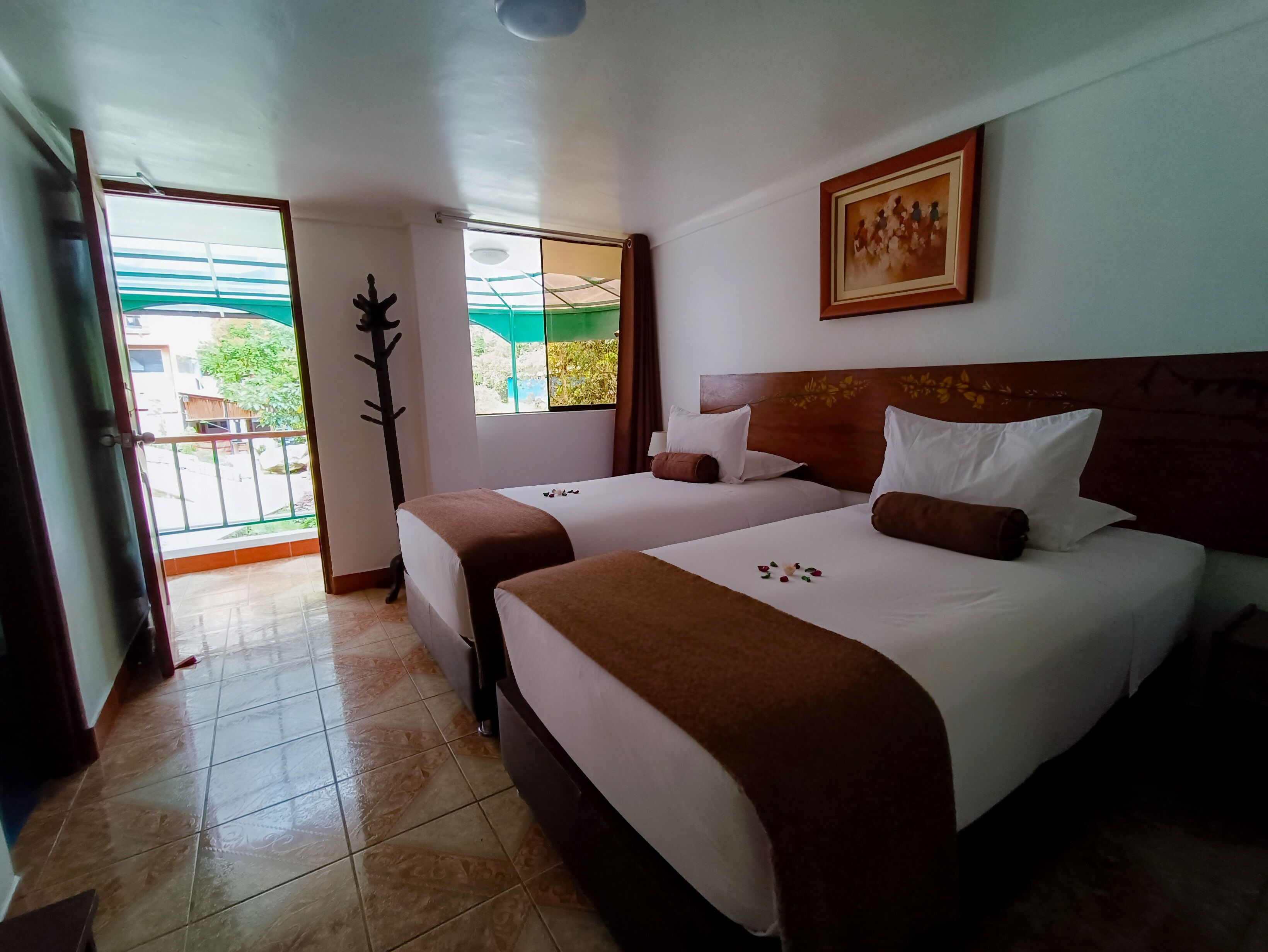 Quarto de hotel com duas camas, uma janela grande e vista para o exterior.
