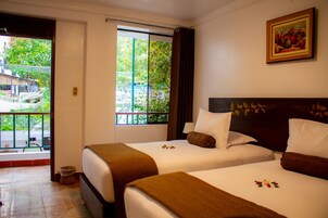 Habitación de hotel con dos camas, una ventana que ofrece vistas a zonas verdes y un cuadro en la pared.