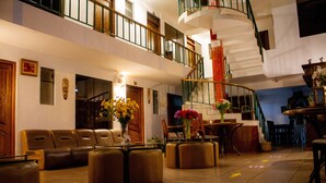 A spacious lobby with leather seating, a central staircase, and a reception desk. - Hotel Retama Machupicchu (Machu Picchu)