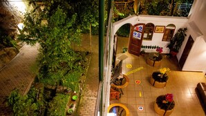 An indoor courtyard with a brick pathway, potted plants, and outdoor seating areas. - Hotel Retama Machupicchu (Machu Picchu)