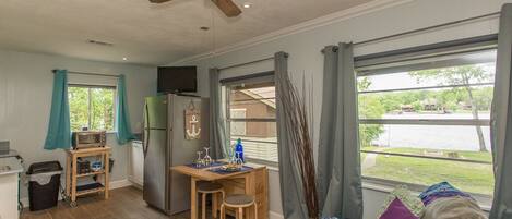Un espacio habitable compacto con kitchenette, comedor y zona de estar con vistas al exterior.
