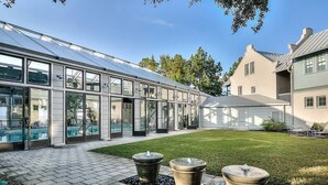 A greenhouse structure with glass walls, a paved patio, and two stone planters.