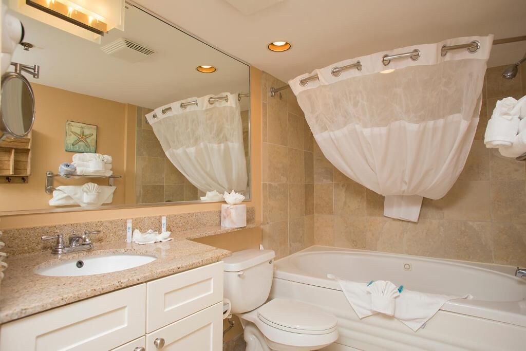 A bathroom with a sink, toilet, and bathtub, featuring a mirror, towel rack, and a starfish decoration.