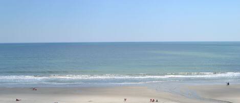A wide sandy beach with a clear view of the ocean.
