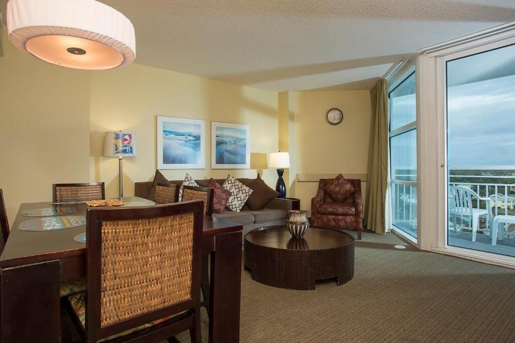Une chambre d’hôtel équipée d’une table à manger, de chaises, d’un canapé, d’une table basse et d’un balcon avec vue.