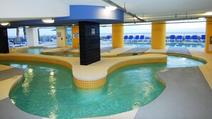 En inomhuspool med flera banor, en livräddarstation och utsikt över havet genom stora fönster.