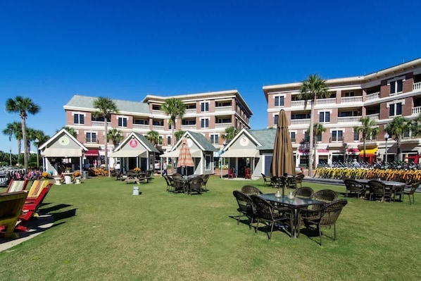 A hotel courtyard with outdoor seating, a pool, and a multi-story building with balconies.