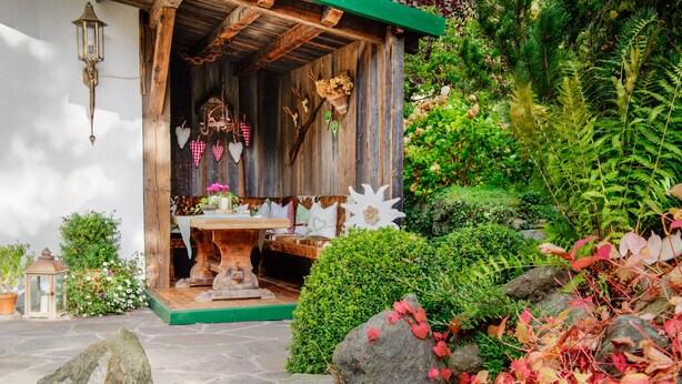 Een rustiek houten huisje met een pad van stenen dat leidt naar een houten deur.