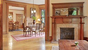 Un salón amplio con chimenea, muebles de madera y un comedor con candelabro.